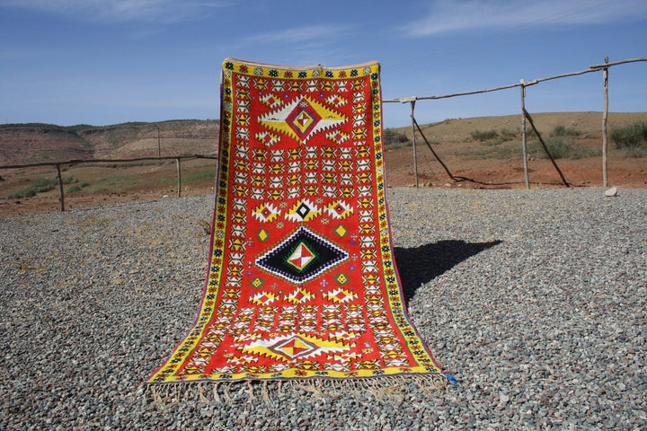 Lifestyle shot of a vintage kilim runner featuring geometric patterns in red, yellow, and black.