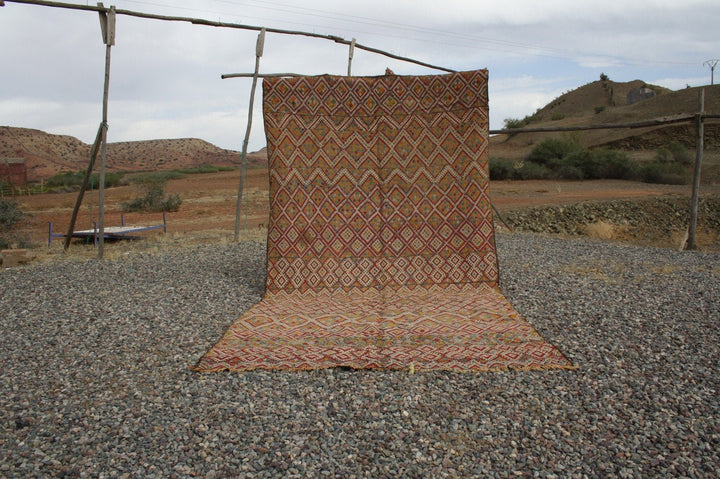 Lifestyle shot of a vintage kilim rug featuring geometric patterns in red and orange.