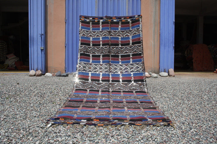 Lifestyle shot of a vintage kilim rug featuring geometric patterns in blue, red, and black.