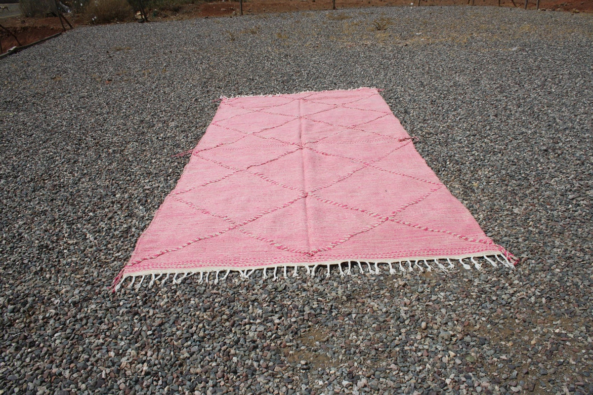 Lifestyle view of a pink Moroccan rug featuring a flat weave and decorative pattern.