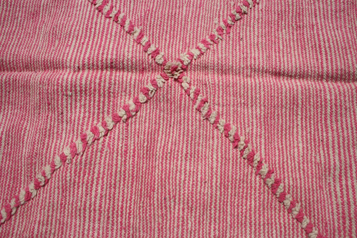 Detail shot of stitched patterns in pink and white on the Moroccan rug.