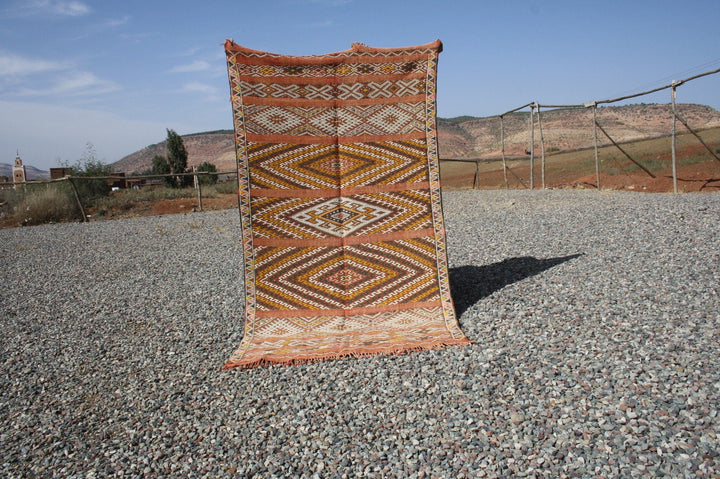 Front view of the vintage kilim rug showcasing geometric patterns in orange and brown.