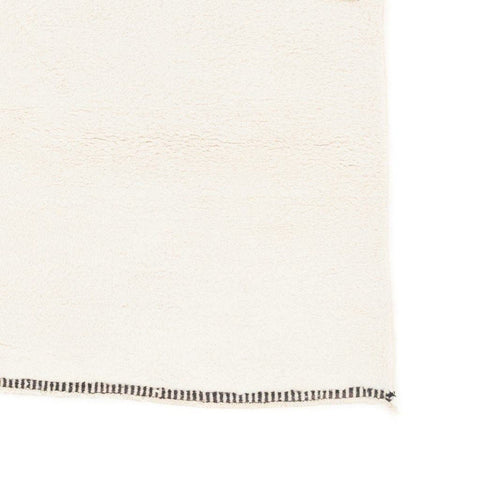 Close-up detail of the smooth finish and simple edge of the cream and gray Moroccan area rug.