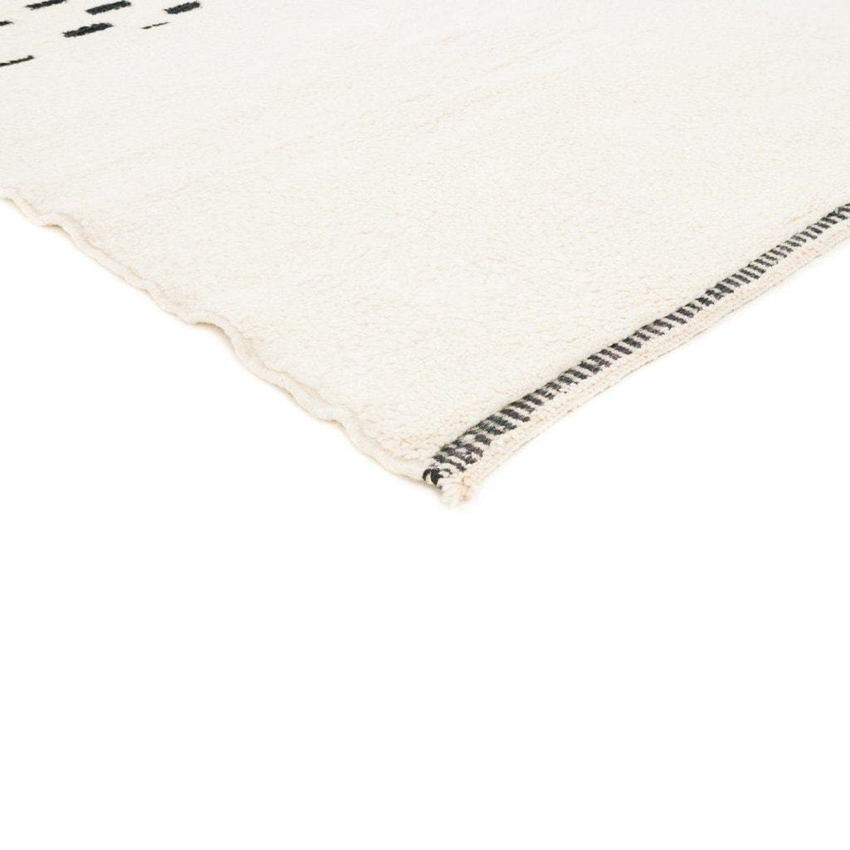 Detail view of the fabric edge and black detailing on the cream Moroccan rug.