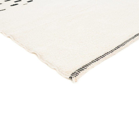 Detail view of the fabric edge and black detailing on the cream Moroccan rug.