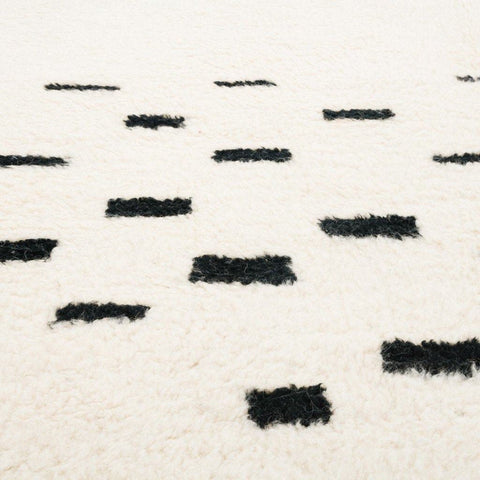 Close-up detail of the textured pattern on the cream and gray Moroccan area rug.