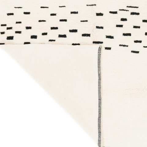 Detail view of the woven texture and black designs on the cream Moroccan rug.