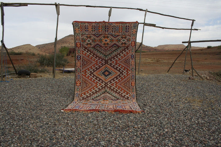 Front view of the vintage kilim rug showcasing geometric patterns in red, blue, and orange.