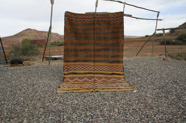 Lifestyle view of a vintage kilim rug featuring a textured weave in brown and yellow.
