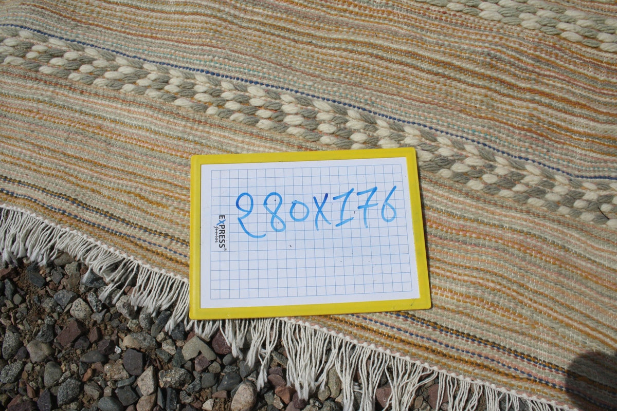 Close-up detail of a beige and brown Moroccan kilim rug highlighting its fringe edges.