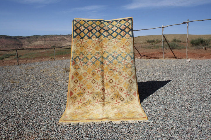 Lifestyle shot of a vintage kilim rug featuring geometric patterns in yellow and brown.