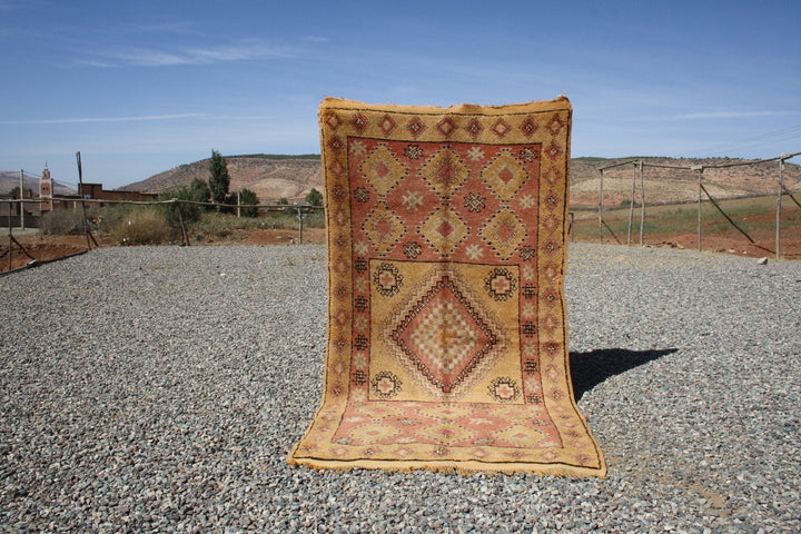 Lifestyle shot of a vintage kilim rug featuring geometric patterns in gold, red, and black.