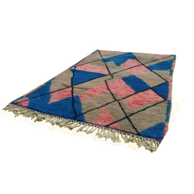 Side view of the blue and pink abstract Moroccan rug showcasing its geometric design and fringe edges.