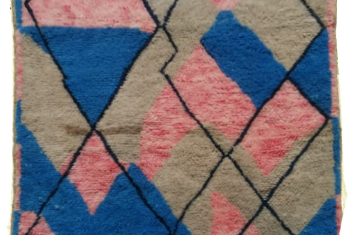 Detail shot of the blue and pink abstract Moroccan rug emphasizing the geometric features and fringe edges.