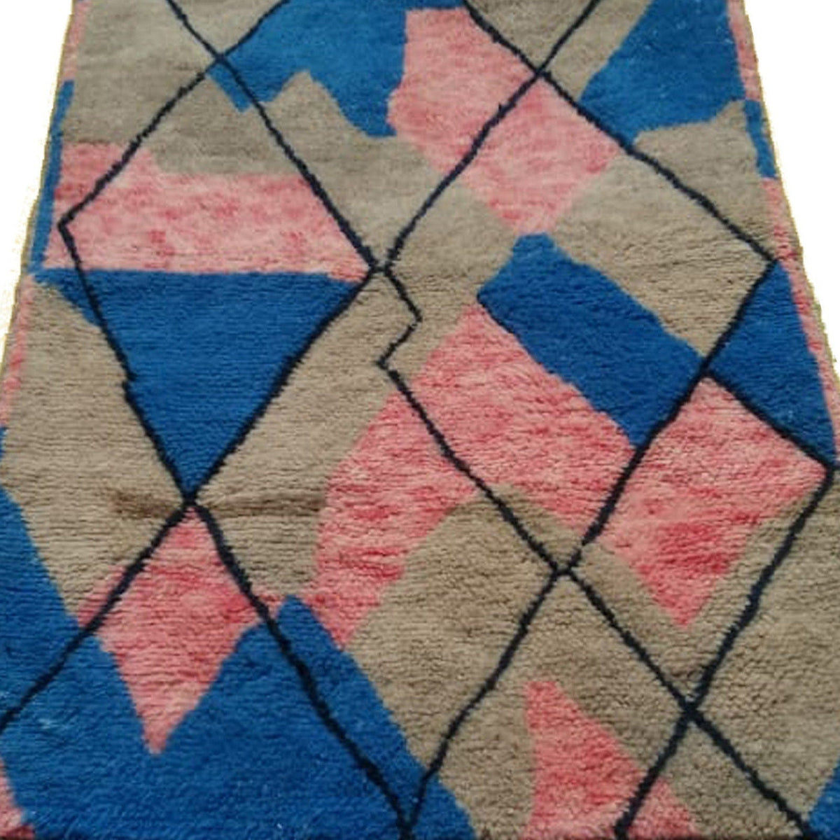 Close-up detail of the blue and pink abstract Moroccan rug highlighting the geometric pattern and fringe.