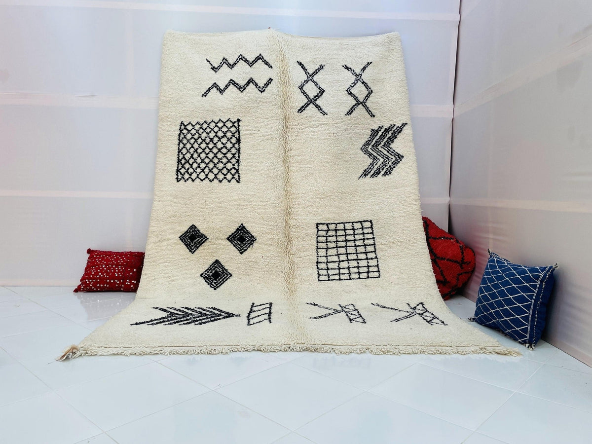 Lifestyle shot of a cream and black geometric Beni Ourain Moroccan rug on a white background.