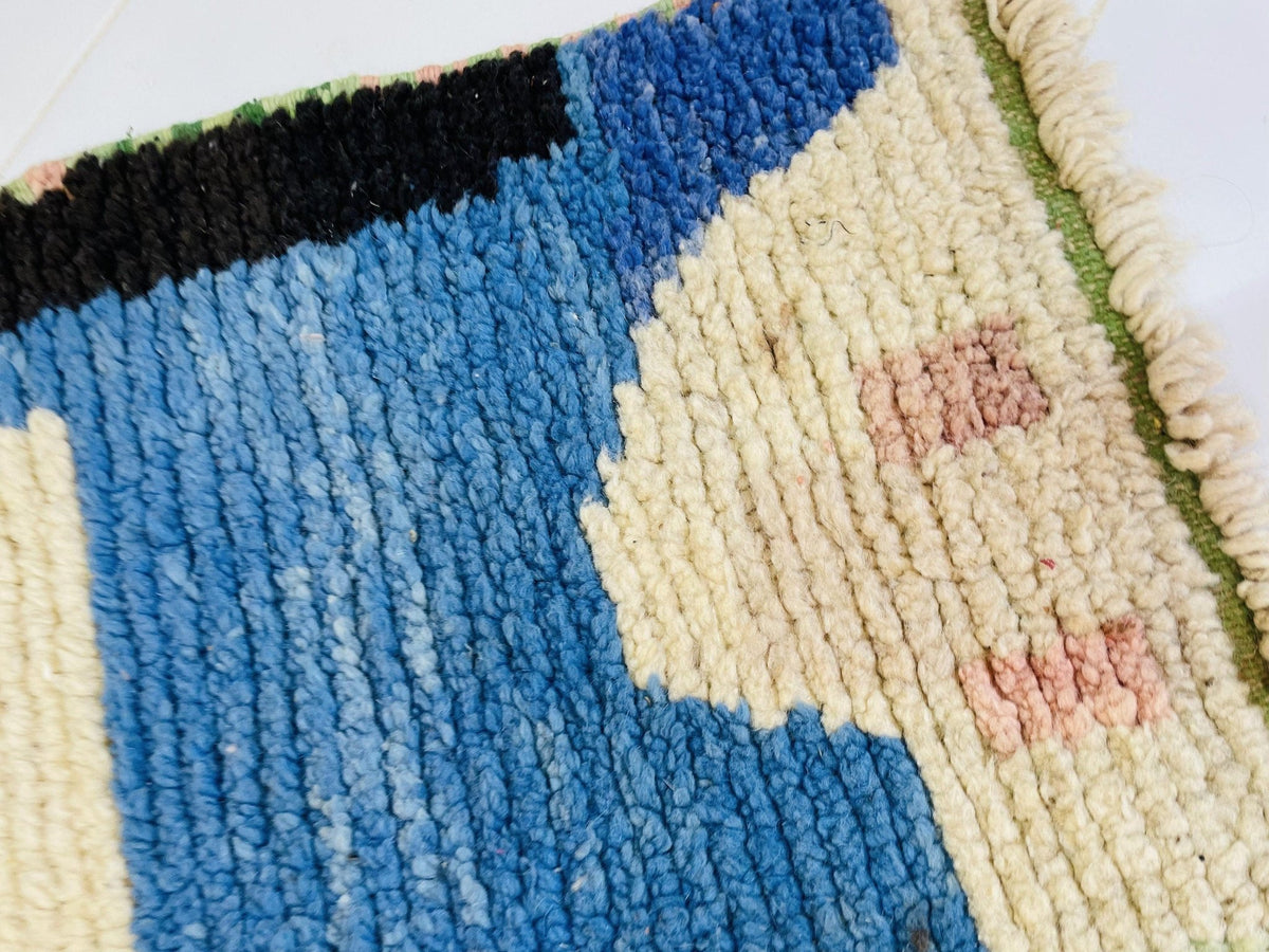 Detail shot of a vintage Moroccan rug highlighting its abstract design in blue, cream, and red.