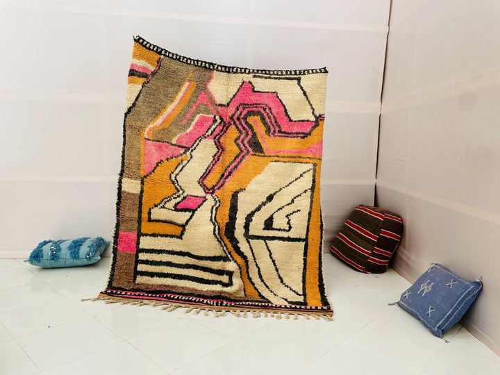 Lifestyle view of the artistic Moroccan rug featuring an abstract design in orange, pink, and black.