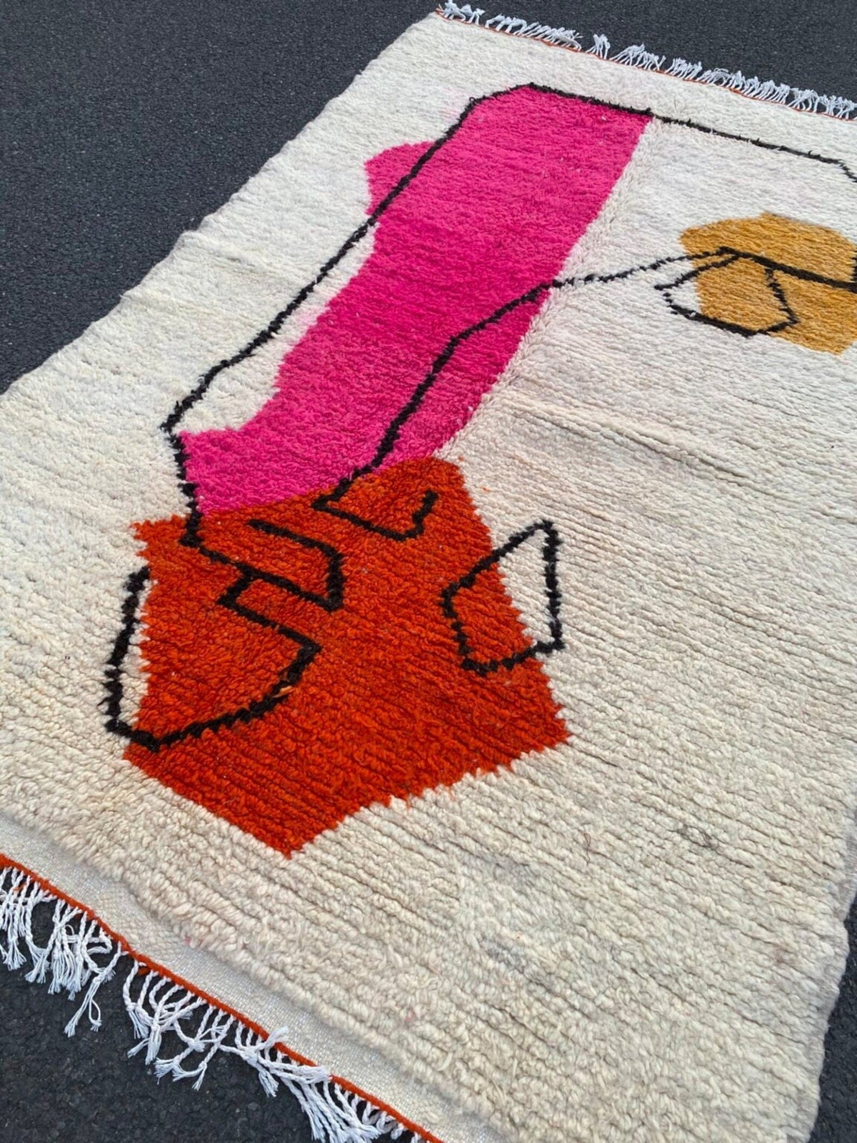 Close-up view of a pink and orange geometric design on the Beni Ourain rug.