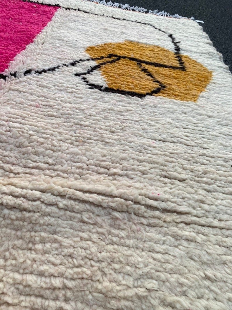 Close-up of a decorative pink and orange rug with a soft texture.