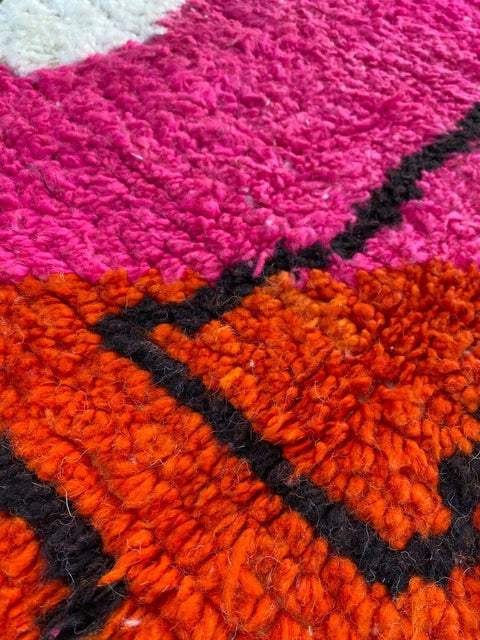 Detail shot of a colorful pink and orange abstract design on the Beni Ourain rug.