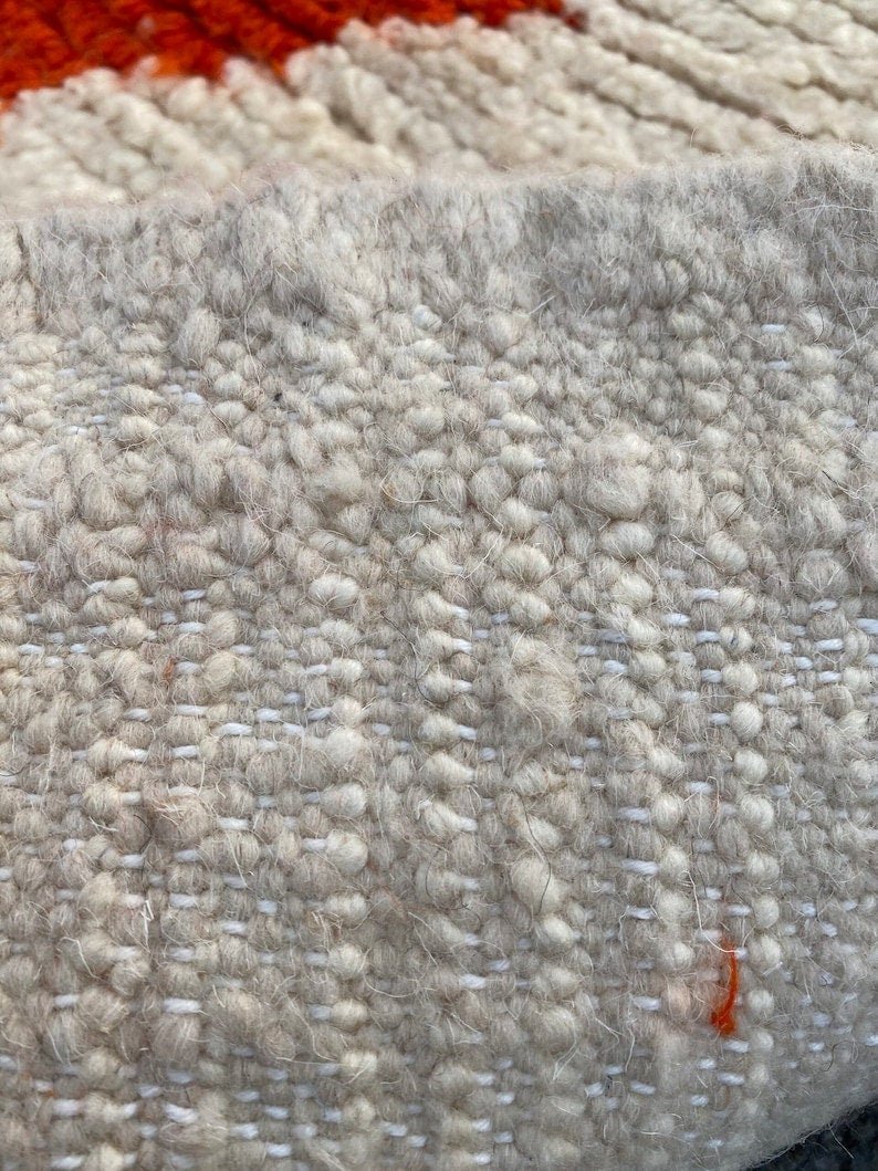 Detail of a red and beige textured surface on the Beni Ourain rug.