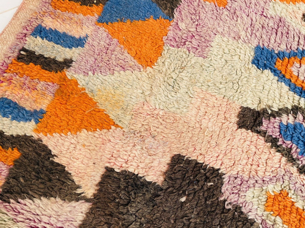 Detail shot of a vintage Moroccan rug with abstract shapes in pink, orange, and black.