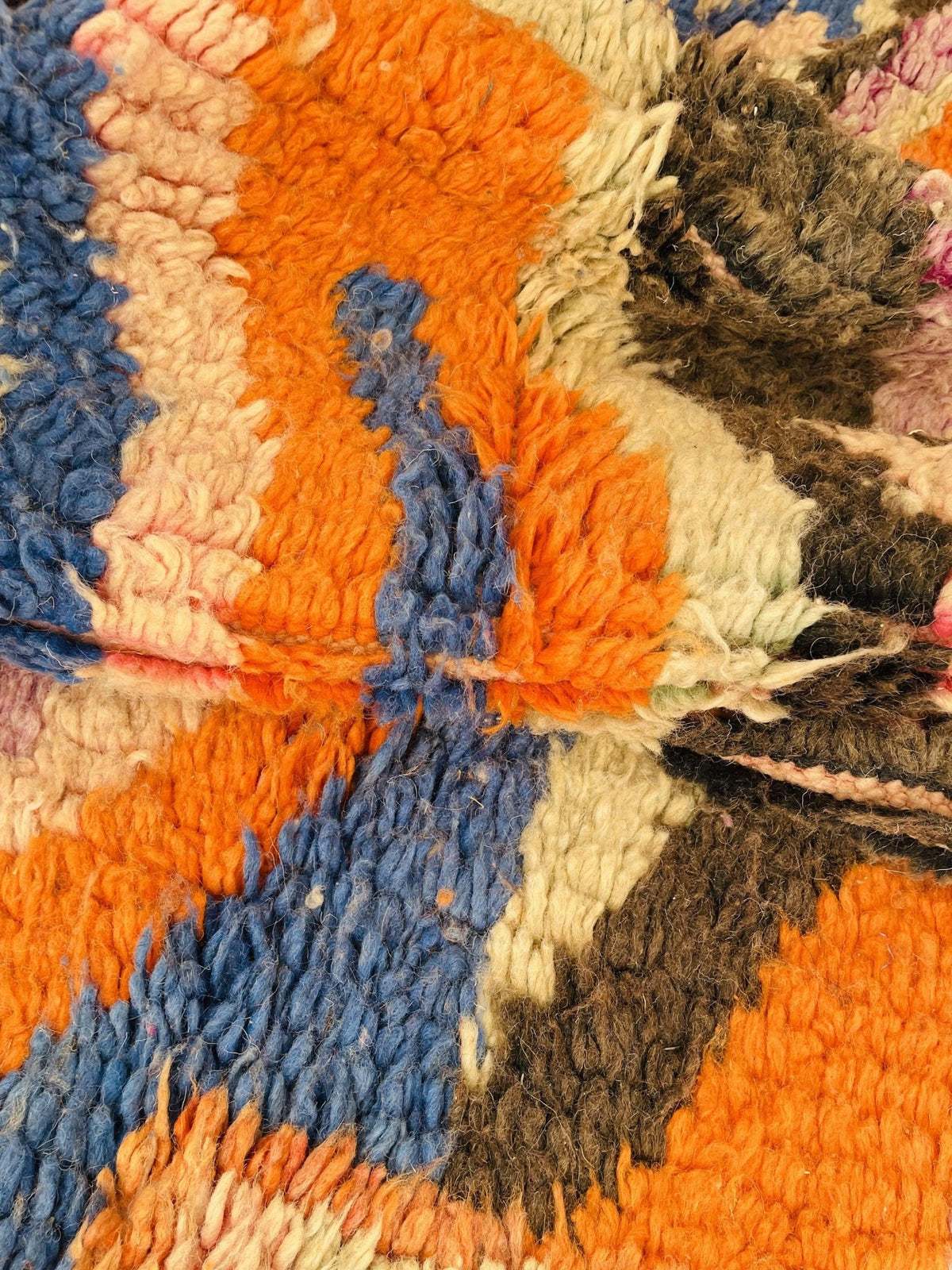 Lifestyle view of a vintage Moroccan rug with vibrant orange and blue abstract patterns.