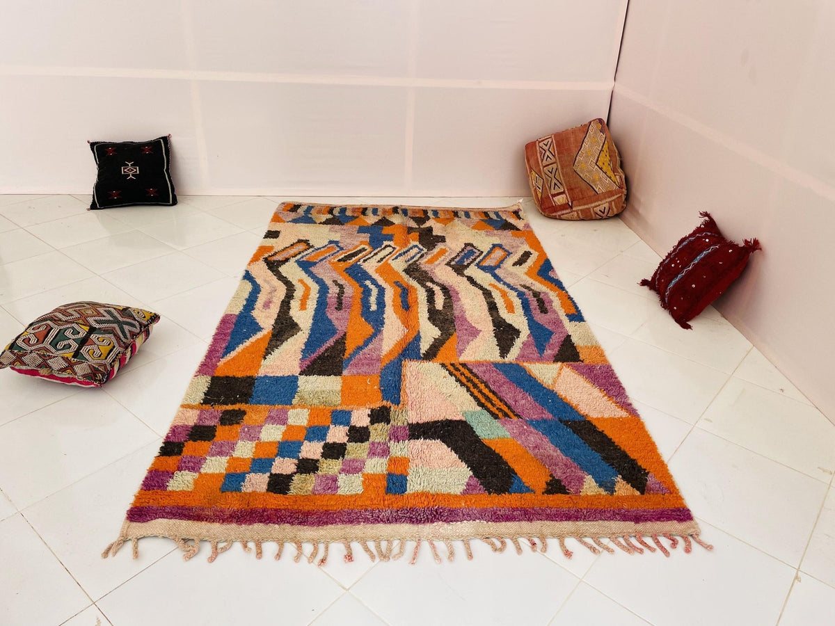 Lifestyle shot of a vintage Moroccan rug showcasing colorful abstract designs in cream and blue.