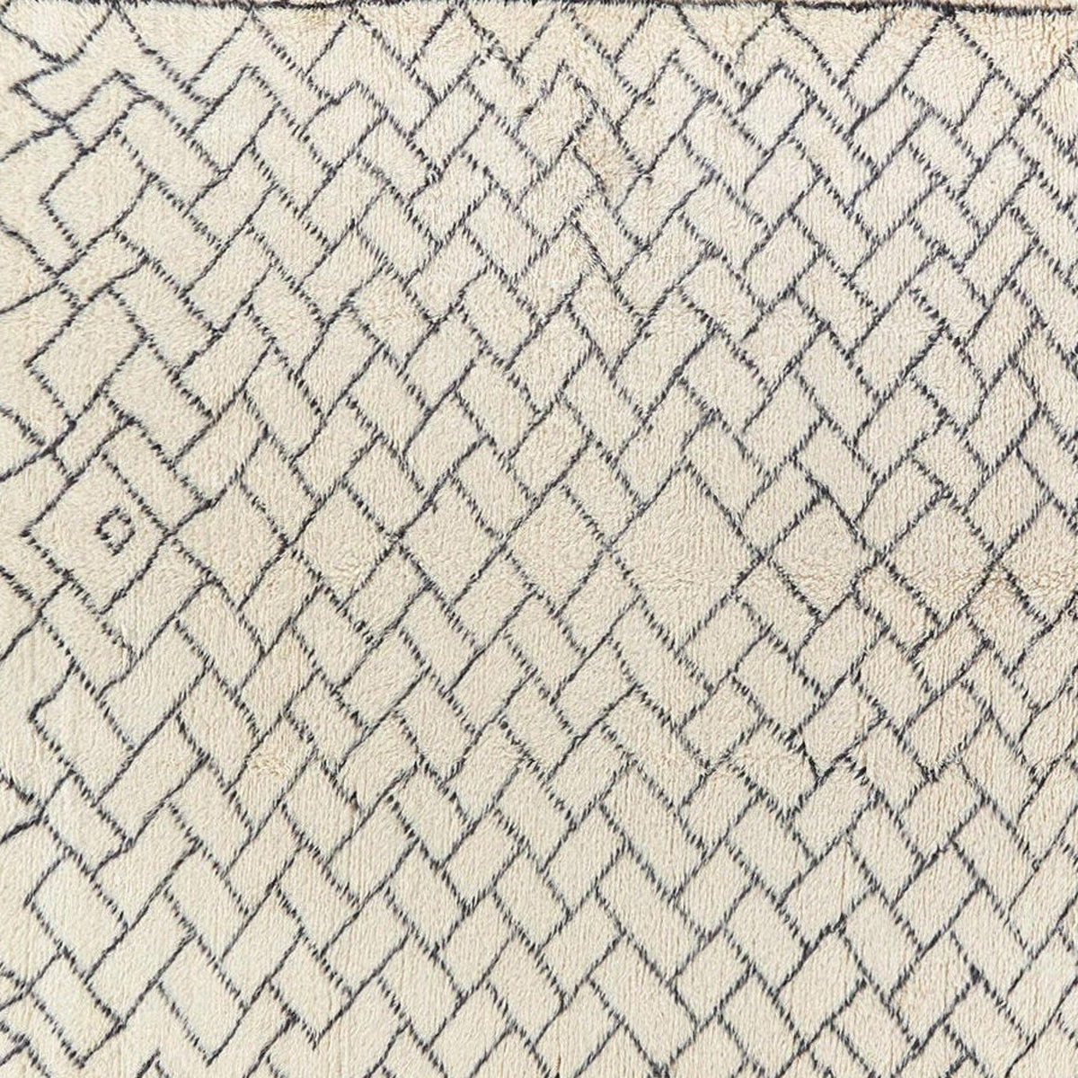Close-up detail of the geometric pattern on the cream minimalist Beni Ourain Moroccan rug in black and off-white.