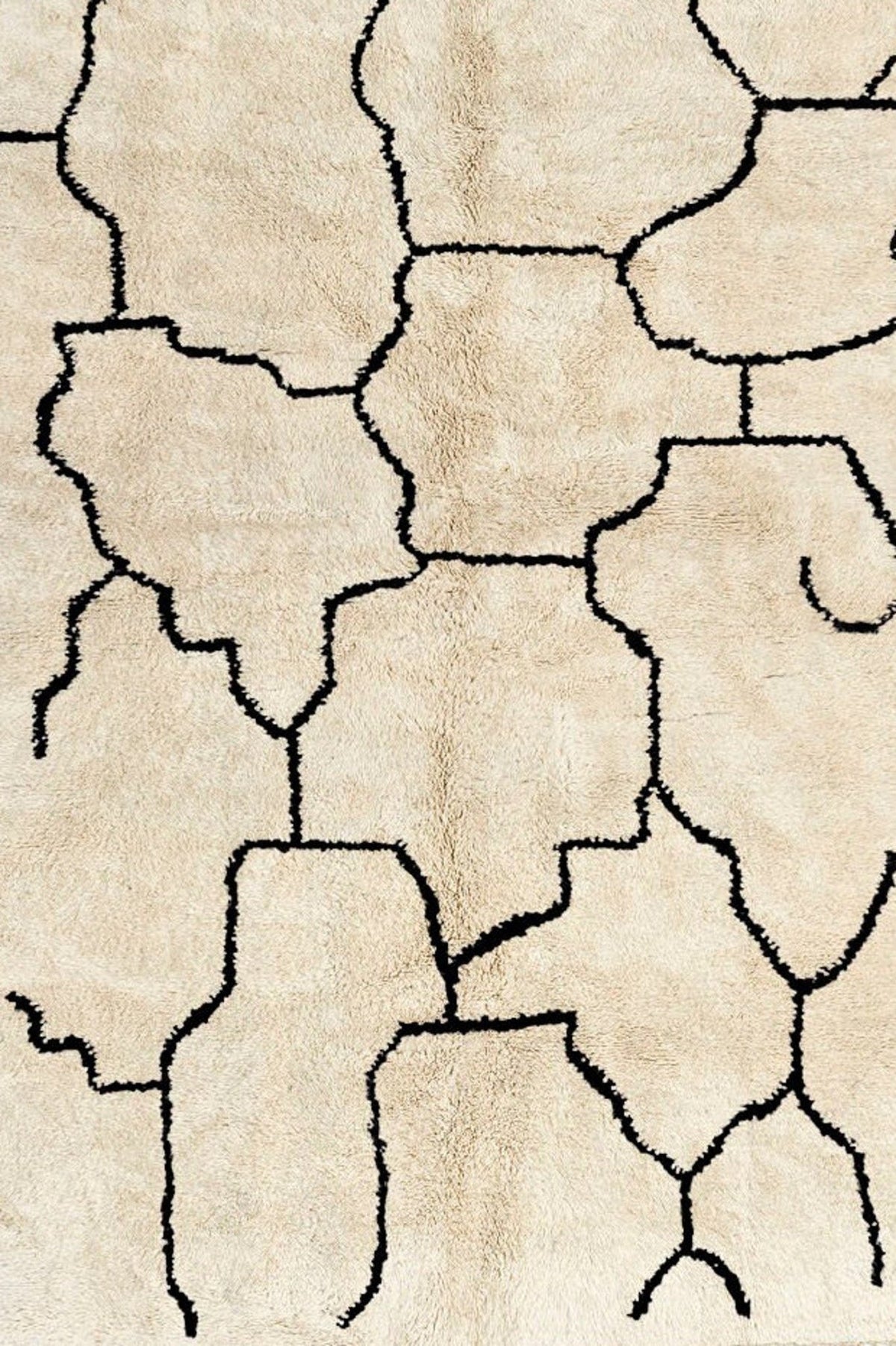 Close-up detail of the beige lattice Beni Ourain Moroccan rug highlighting the abstract black and off-white pattern.