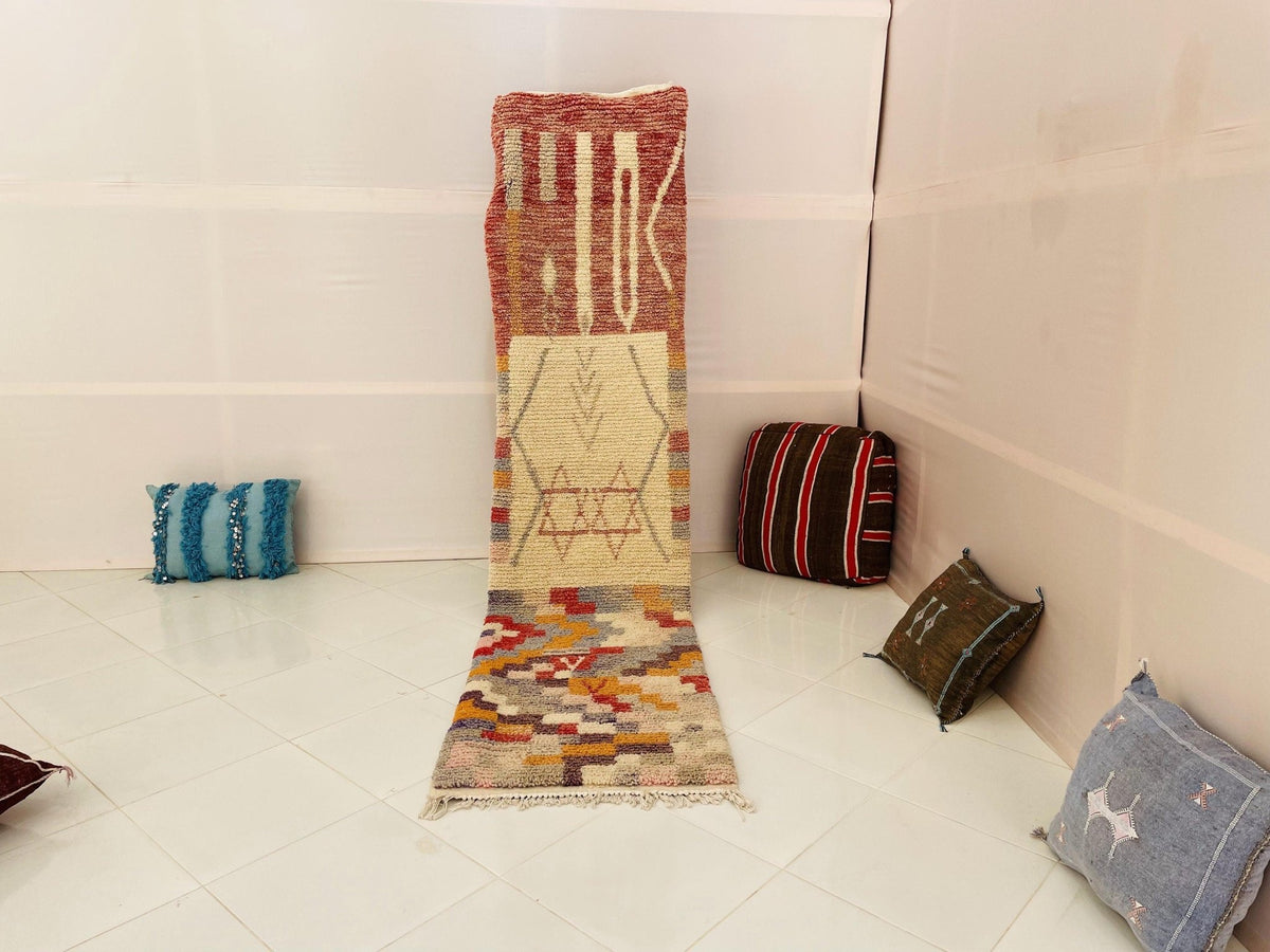 Lifestyle shot of a red and orange geometric runner rug in a studio setting.