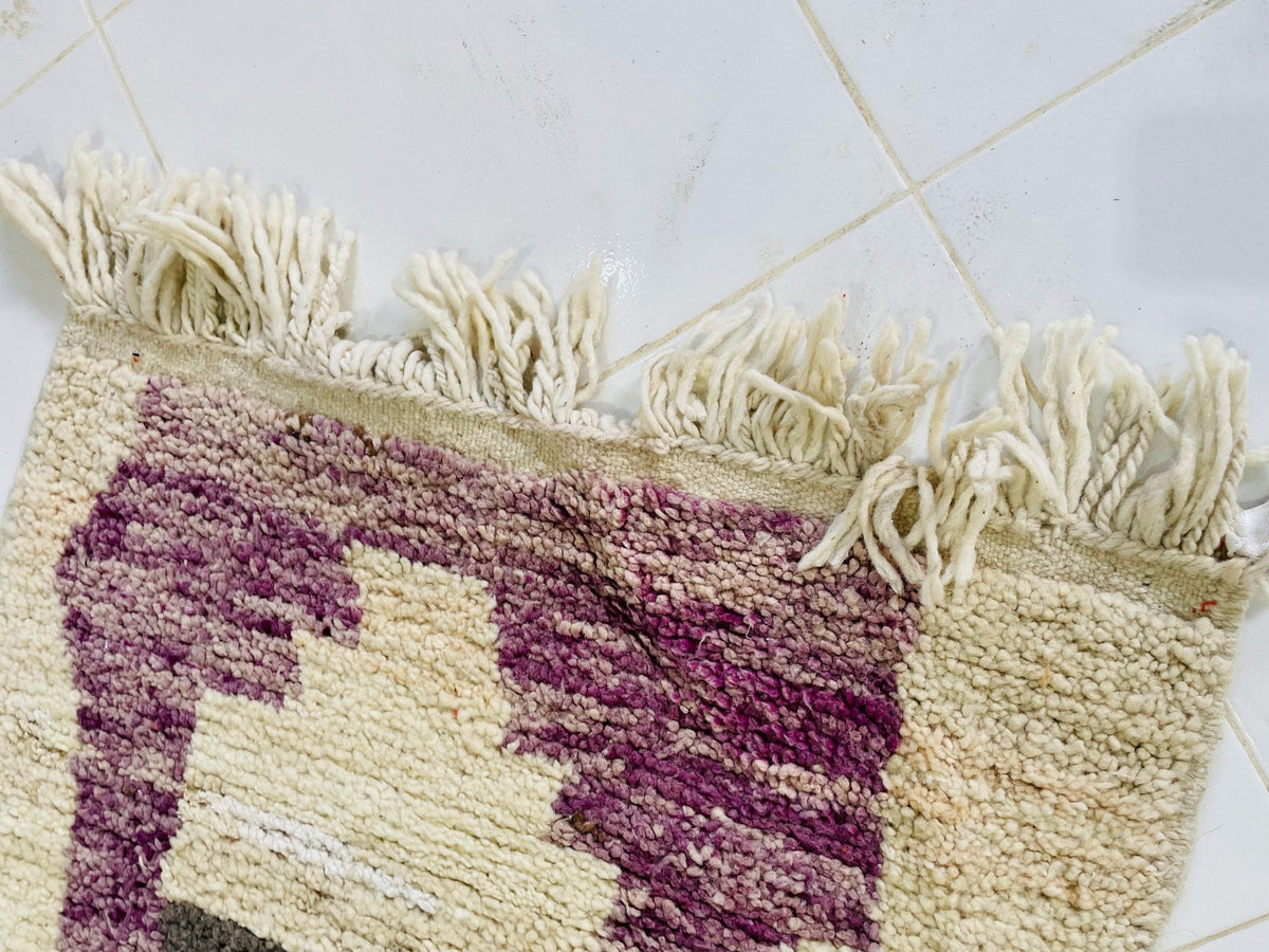 Detail close-up of the textured surface of the rug featuring a striped pattern in cream and purple.