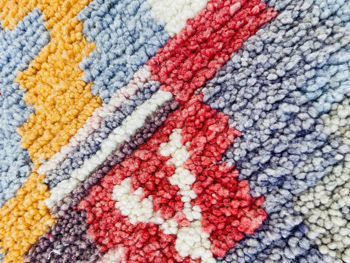 Close-up detail of a colorful woven rug with an abstract pattern.