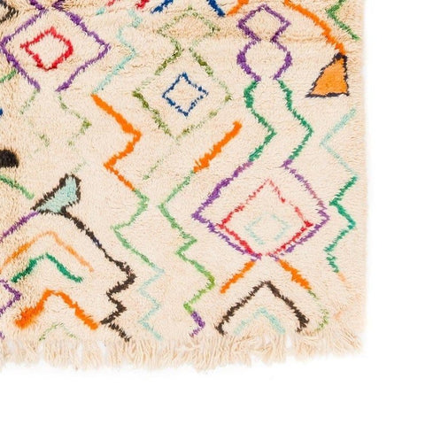 Close-up detail of a multicolor Moroccan rug featuring geometric patterns and fringe edges.