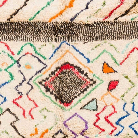 Close-up detail of a colorful Moroccan area rug featuring a diamond pattern in red, blue, and green.