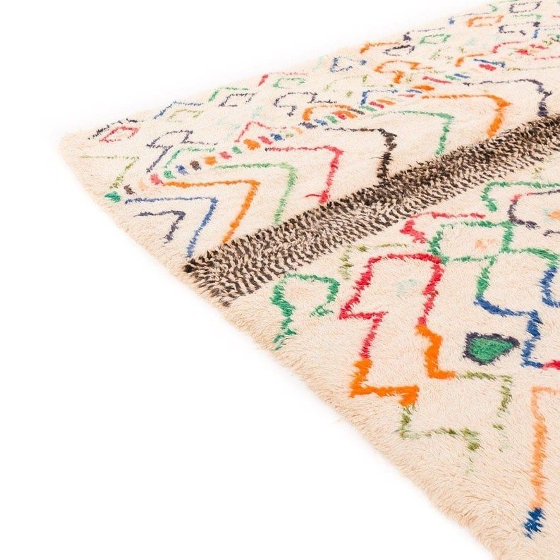 Close-up detail of a multicolor Moroccan rug showcasing geometric patterns and fringe edges.