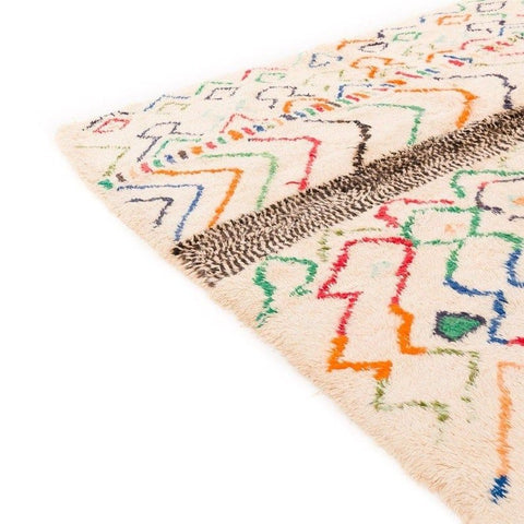 Close-up detail of a multicolor Moroccan rug showcasing geometric patterns and fringe edges.