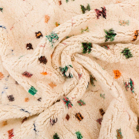 Detail shot of a colorful area rug with a textured surface and polka dot pattern.