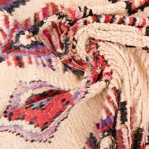Close-up of the fringed edge of the Azilal rug with woven texture in cream, red, and purple.