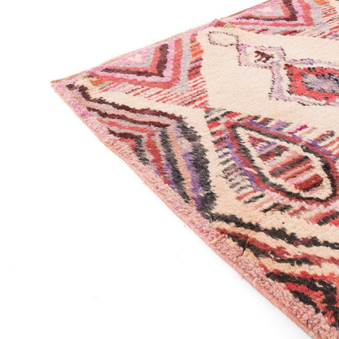 Close-up of the textured edge of the pink geometric Azilal rug with colorful patterns.