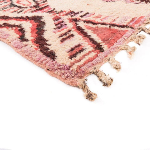 Close-up detail of the Azilal rug with fringe edges and geometric patterns in pink and cream.