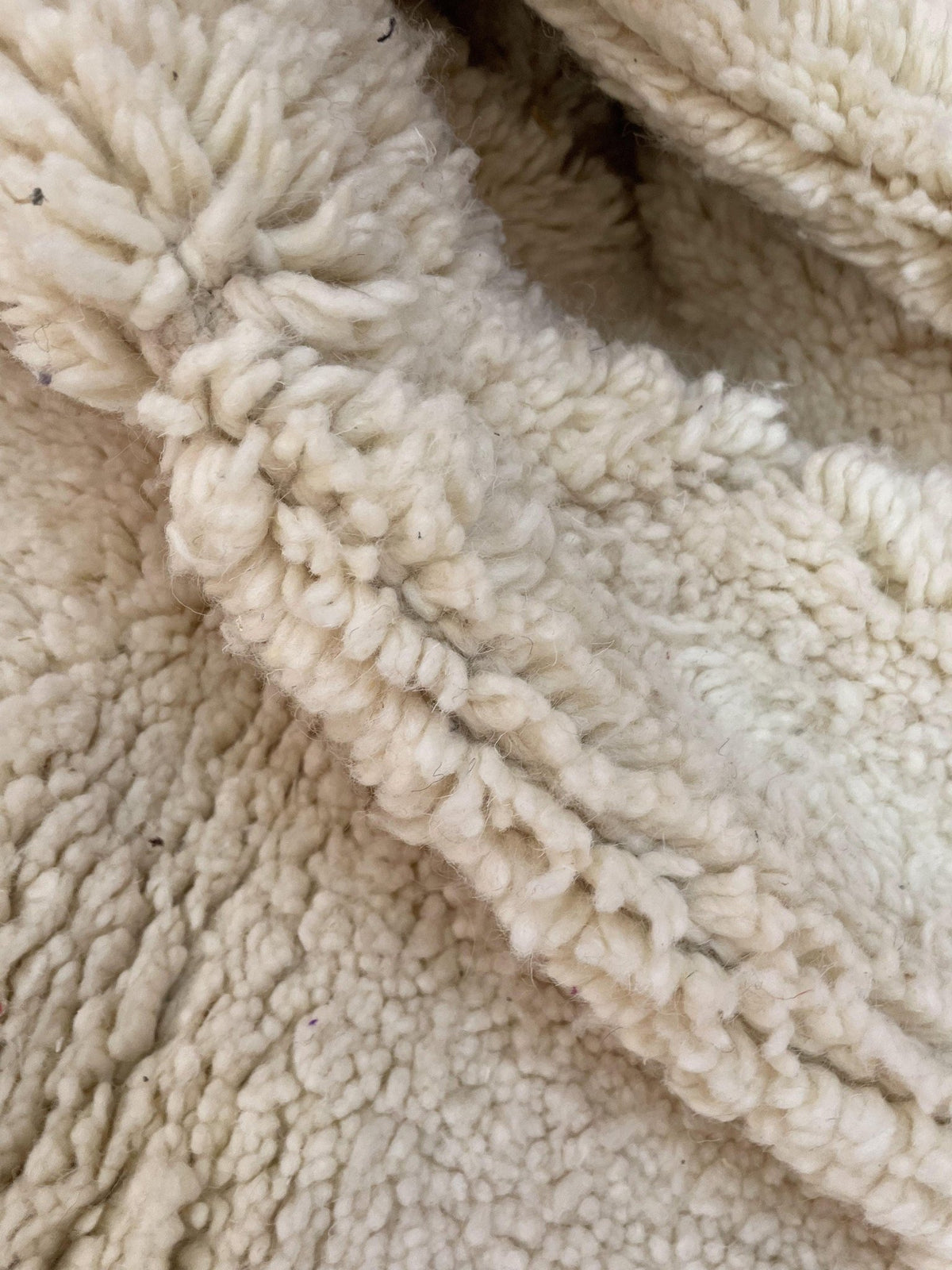 Detail close-up showcasing the textured surface and woven pattern of a beige and cream Moroccan rug.