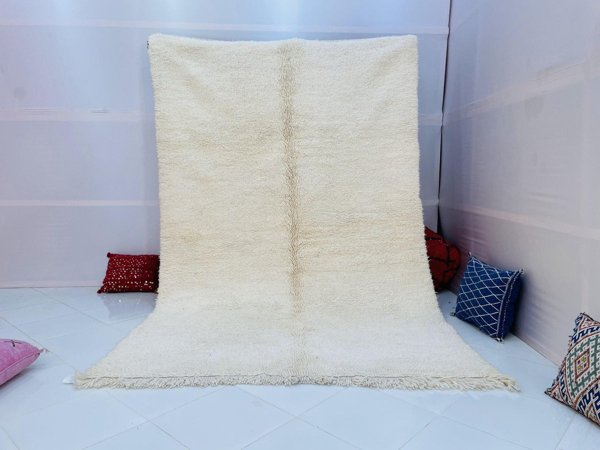 Lifestyle shot of a beige and blue striped Moroccan rug in a studio setting.