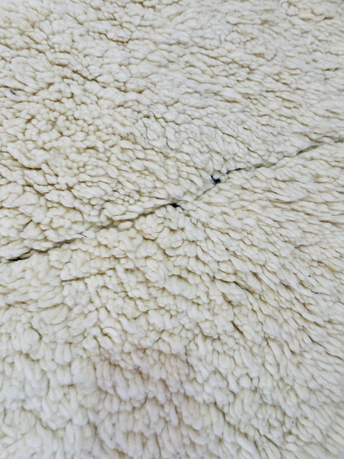 Detail close-up of a white wool rug featuring an abstract pattern and soft texture.