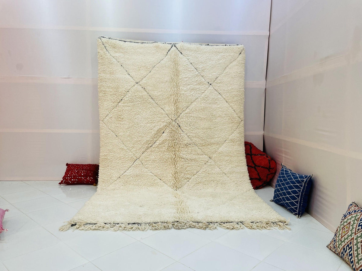 Lifestyle shot of a cream and beige Moroccan rug with an abstract design in a studio setting.