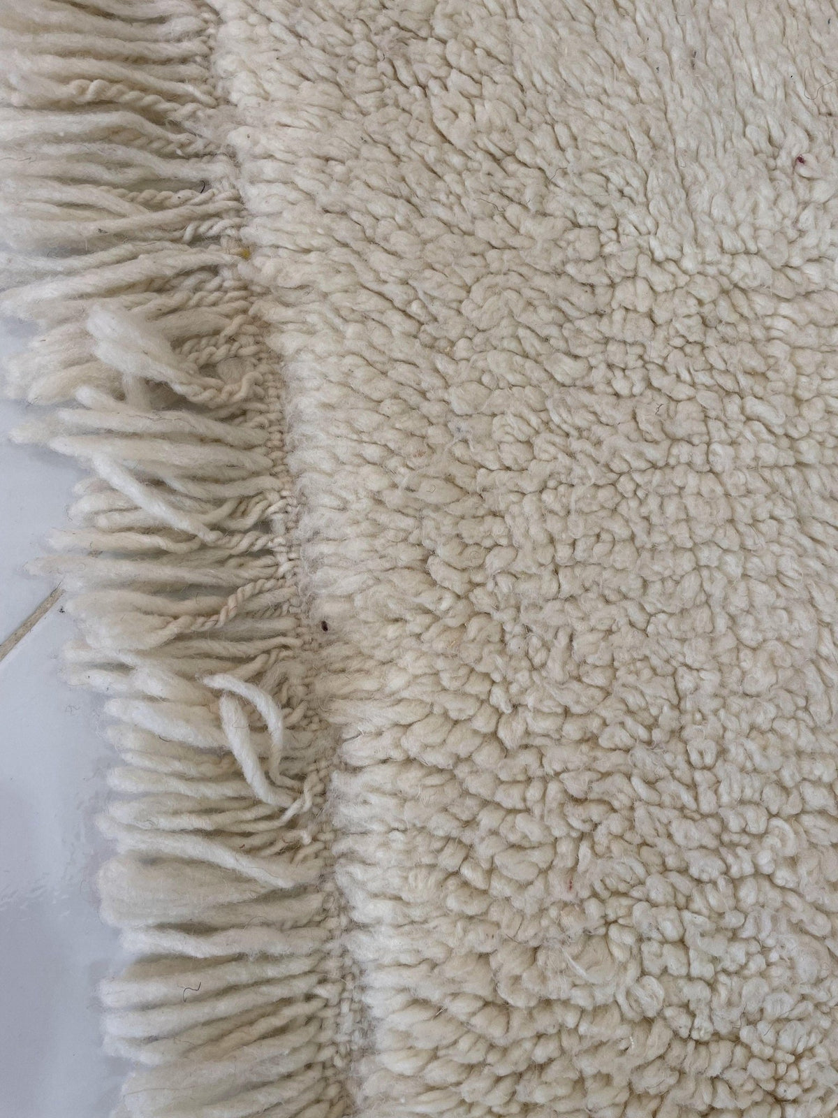 Lifestyle shot of a beige and blue striped Moroccan rug in a studio background.