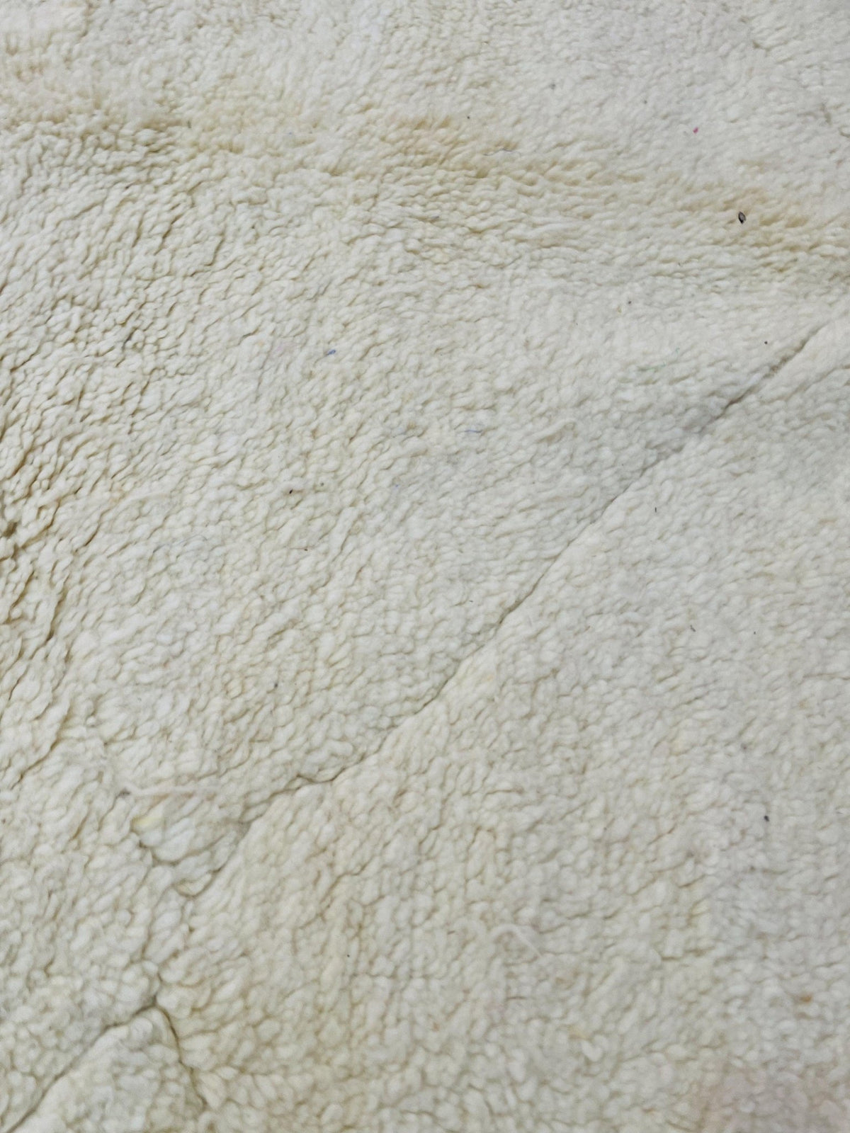 Detail close-up of the textured pattern on a cream and beige Moroccan rug with natural fibers.