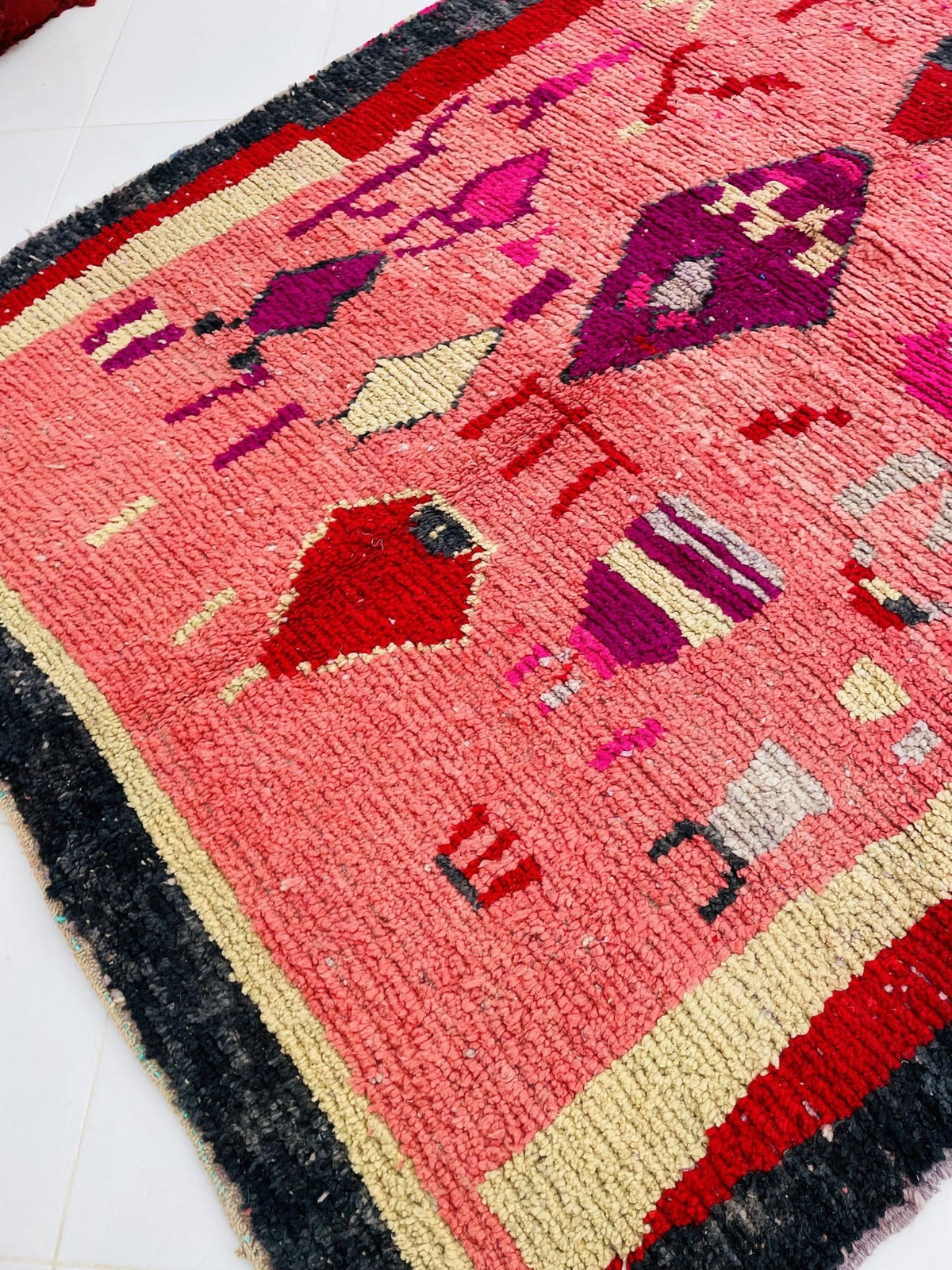 Detail view of a pink vintage Moroccan rug featuring colorful patterns against a contrasting background.