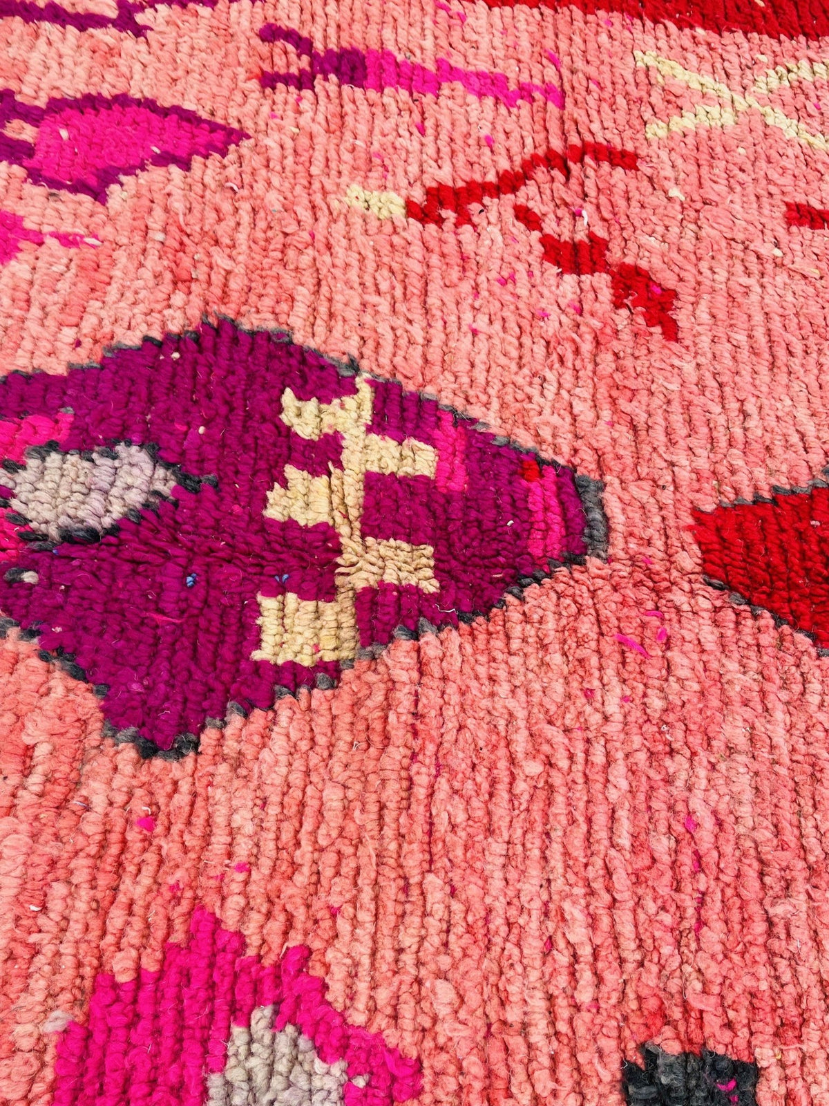 Detail shot of a pink vintage Moroccan rug with geometric patterns and vibrant colors.